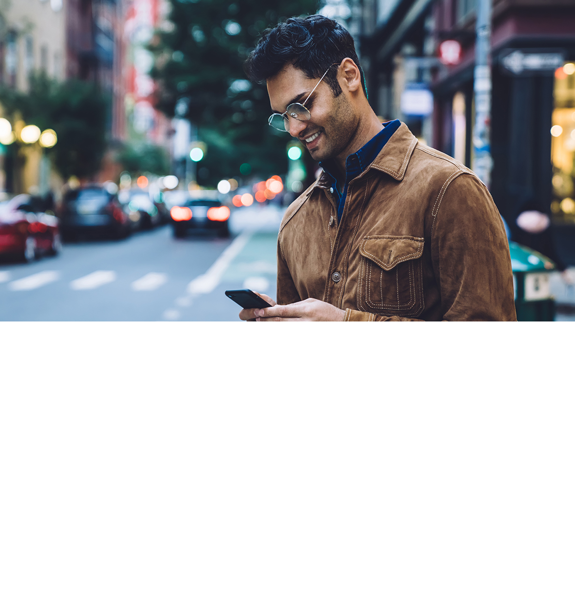 Ethnic man with glasses on the street looking down at his iphone