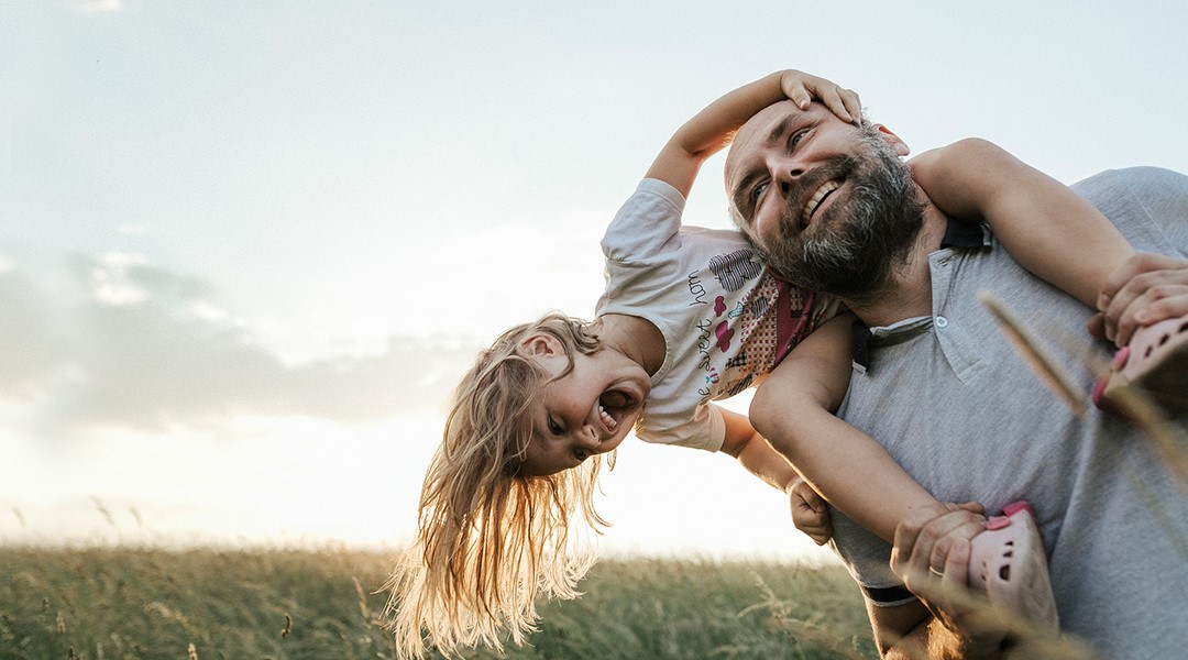 Little girl on dad's shoulders smiling and laughing